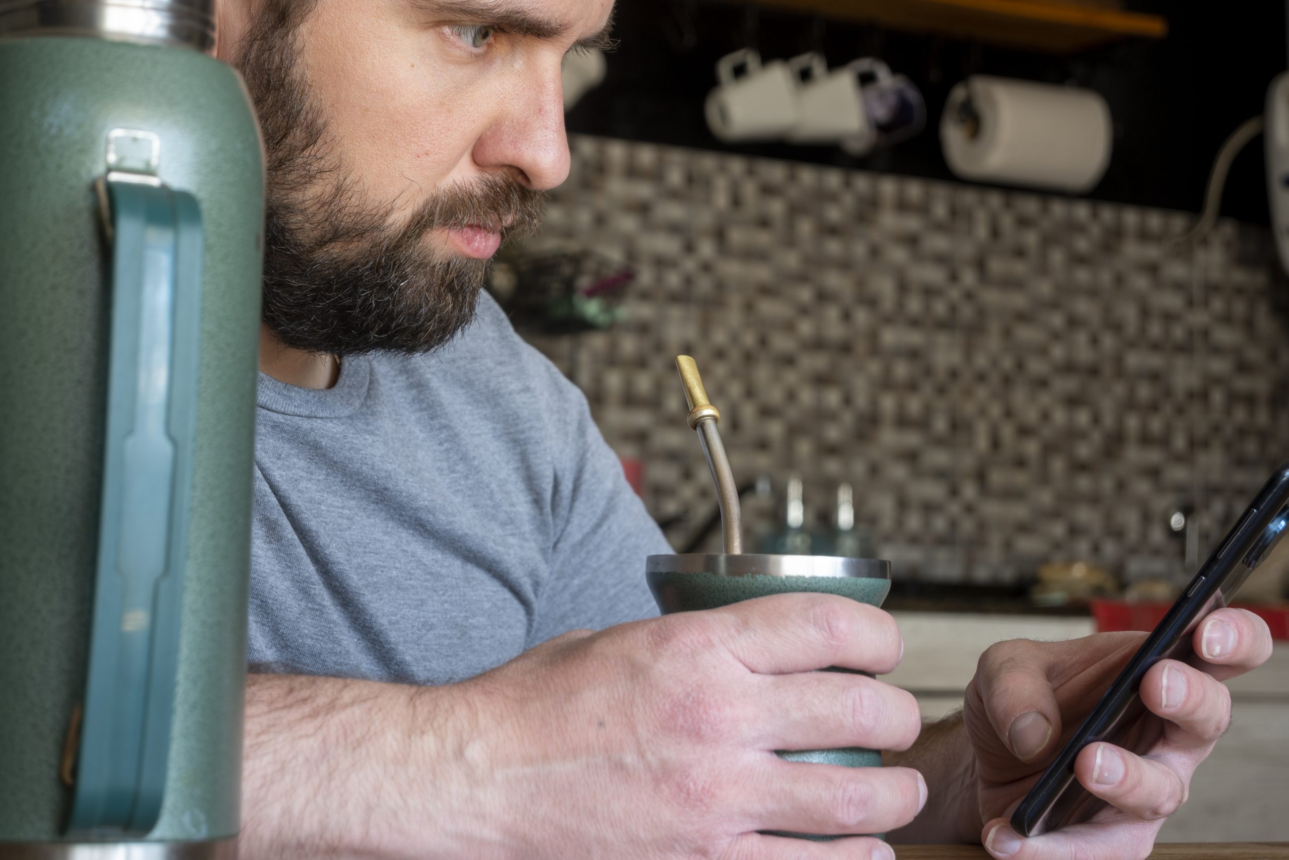 Latin man drinking mate in the kitchen. un buraliste utilisant les réseaux sociaux en situation réelle